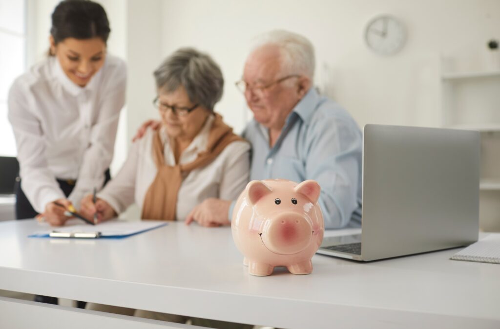 Happy retired senior couple sign life insurance paper at table in brokers office