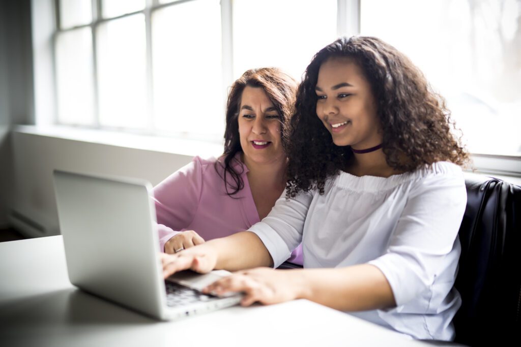 A Mother And Teenage Daughter Looking At Laptop Together